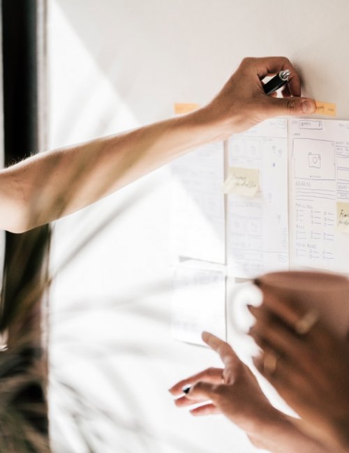 A team of designers place sticky notes and labels on a paper wireframe during a workshop
